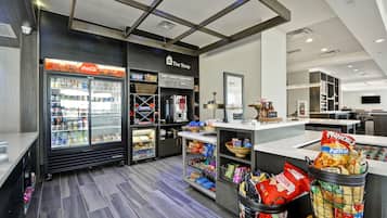 Ett modernt butiksutrymme med ett kylskåp för varuexponering, hyllor med snacks och en disk med en skylt som visar texten ”Butiken”.