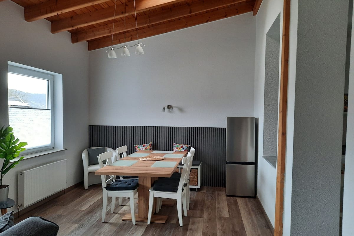 Una cocina moderna con una mesa de comedor, sillas, un refrigerador y una ventana con vistas.
