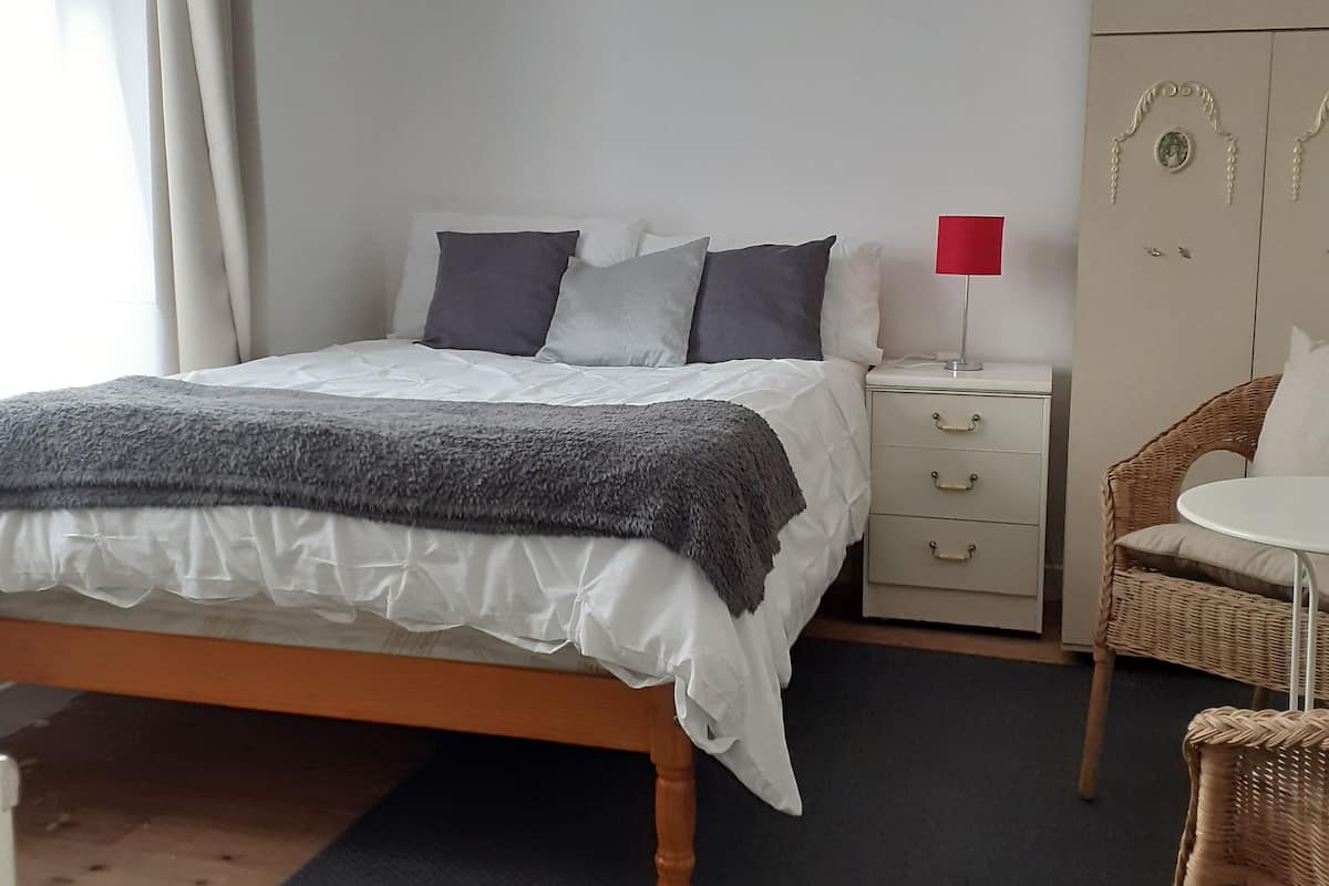 Ein ordentlich eingerichtetes Schlafzimmer mit Bett, Nachttisch und Kleiderschrank.