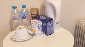 Et lille rundt bord med en hvid kop, to vandflasker, en kaffemaskine, en tissueske og en pakke tissues.