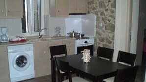 Une cuisine compacte équipée d’un lave-linge, d’une cuisinière et d’un coin repas avec des chaises.