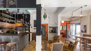 A bar area with stools, a counter with bottles, and a menu on the wall. - The Grand Meshmosh Hotel (Beirut)
