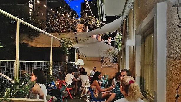 An outdoor seating area with tables and chairs, surrounded by plants and umbrellas. - The Grand Meshmosh Hotel (Beirut)