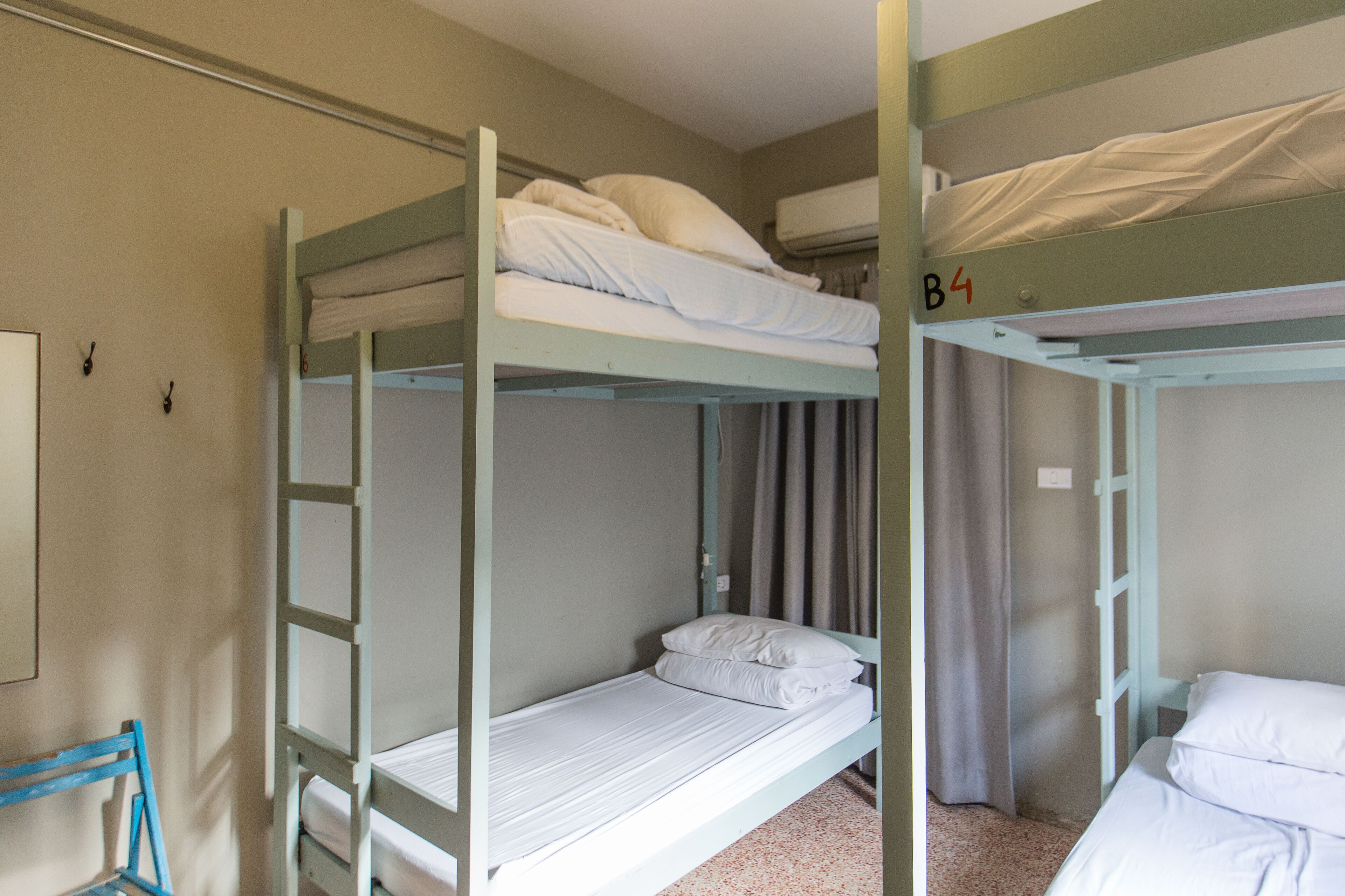 Dormitorio con literas, dos camas, una escalera y una cortina.