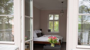 A bedroom with a bed, a window, and a table with flowers. - Herrenhaus Röddelin (Templin)