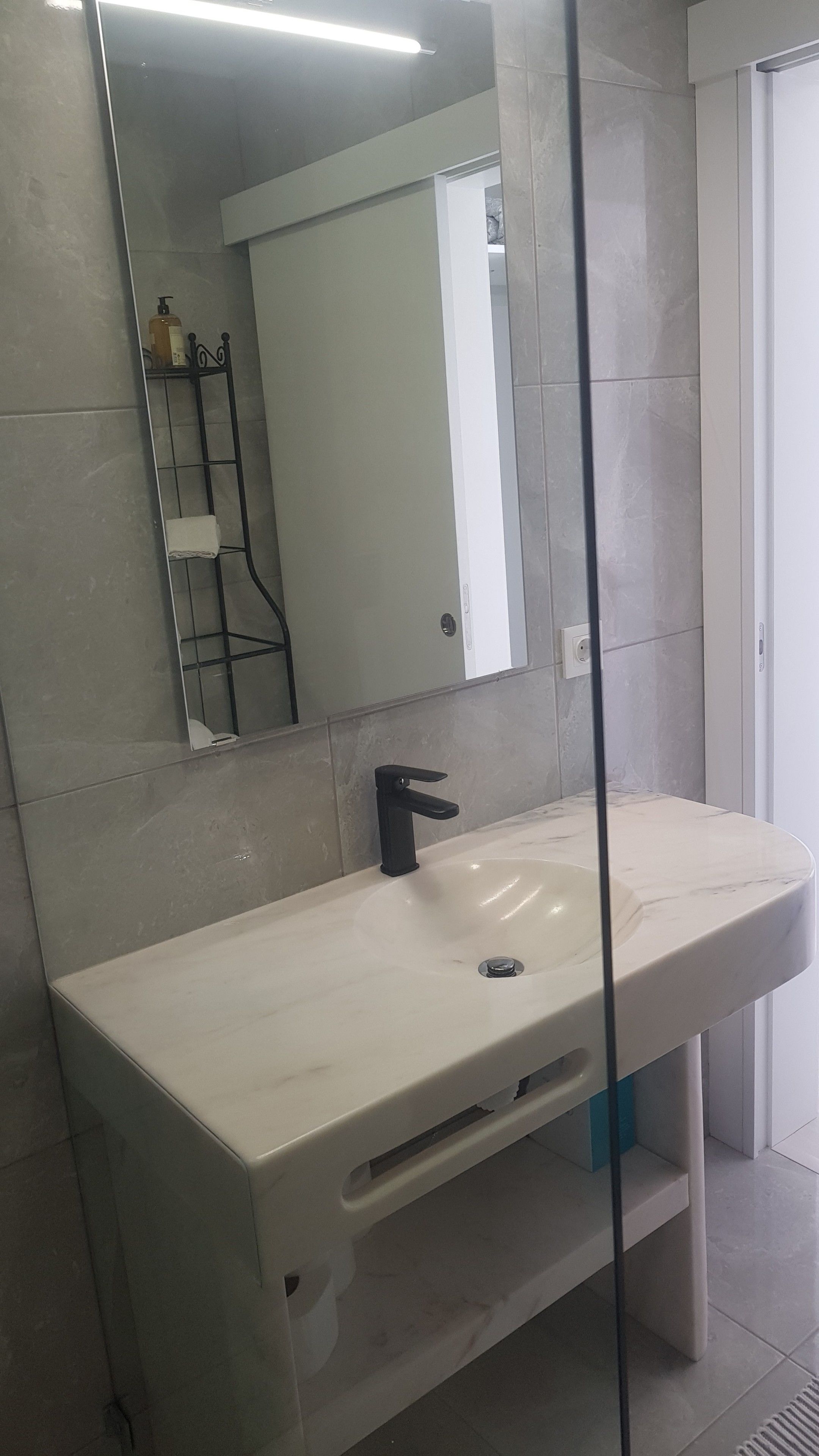 A bathroom with a white sink, a black faucet, and a mirror.