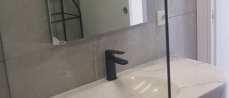 A bathroom with a white sink, a black faucet, and a mirror.