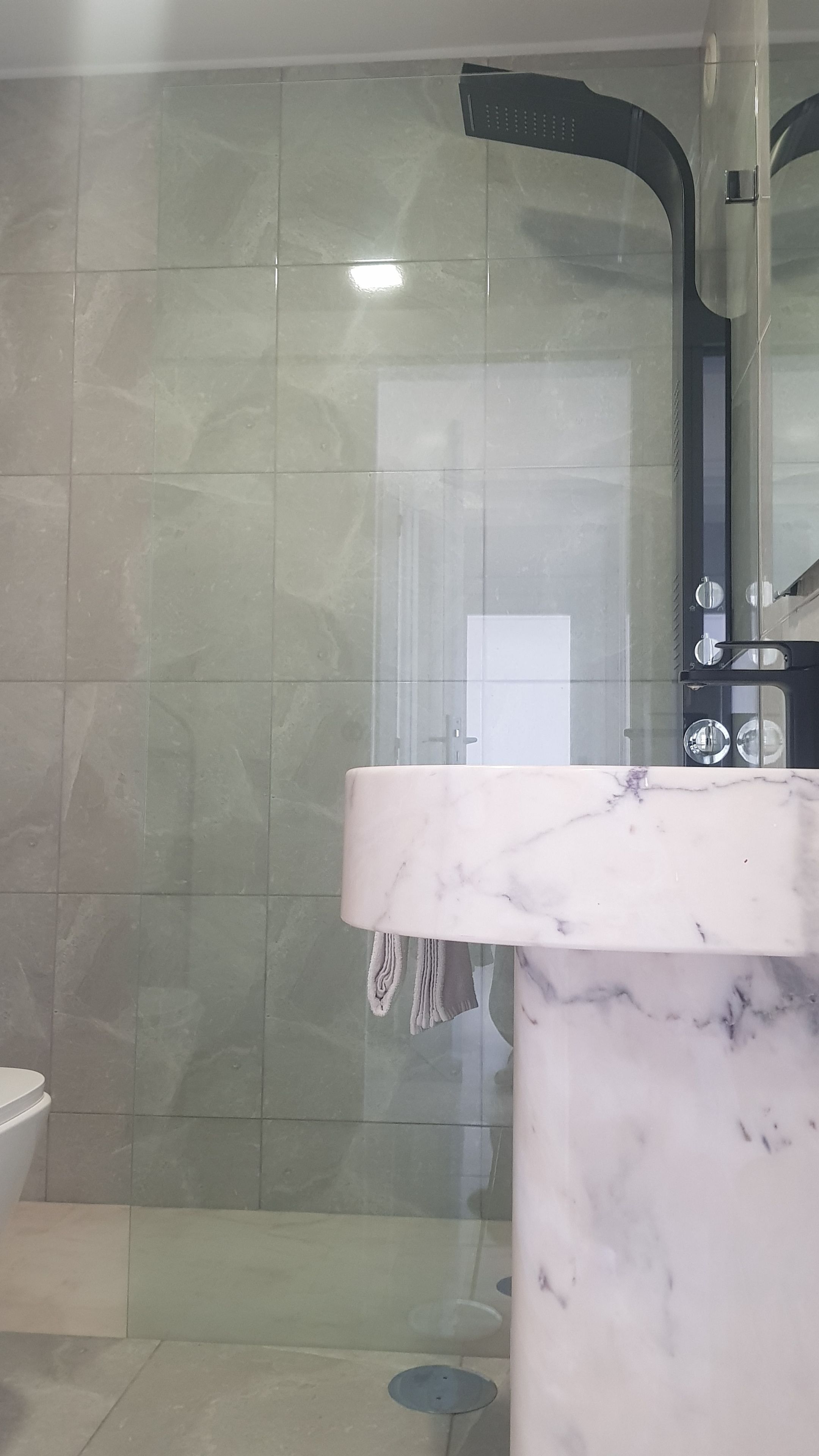 Un baño con cabina de ducha de vidrio, un lavamanos de mármol y un inodoro.