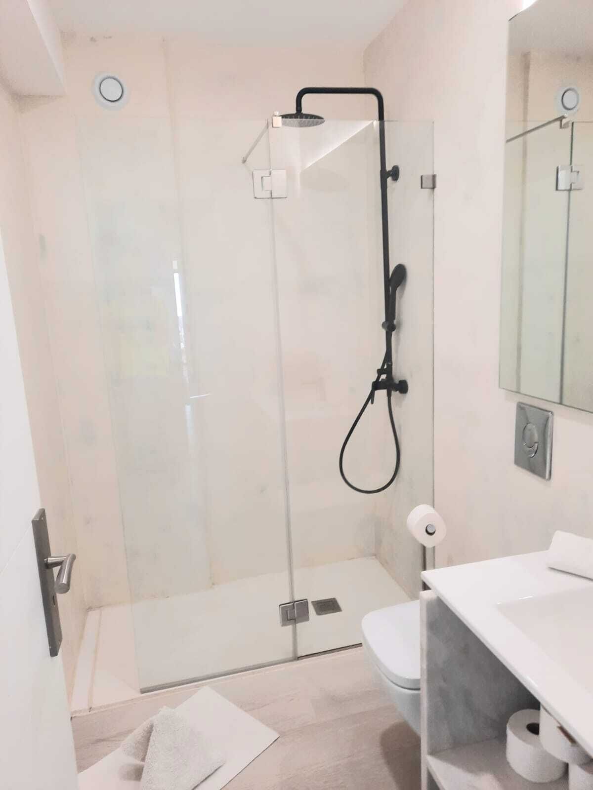 Une salle de bain moderne avec une douche à parois de verre, des toilettes et un lavabo avec un miroir.