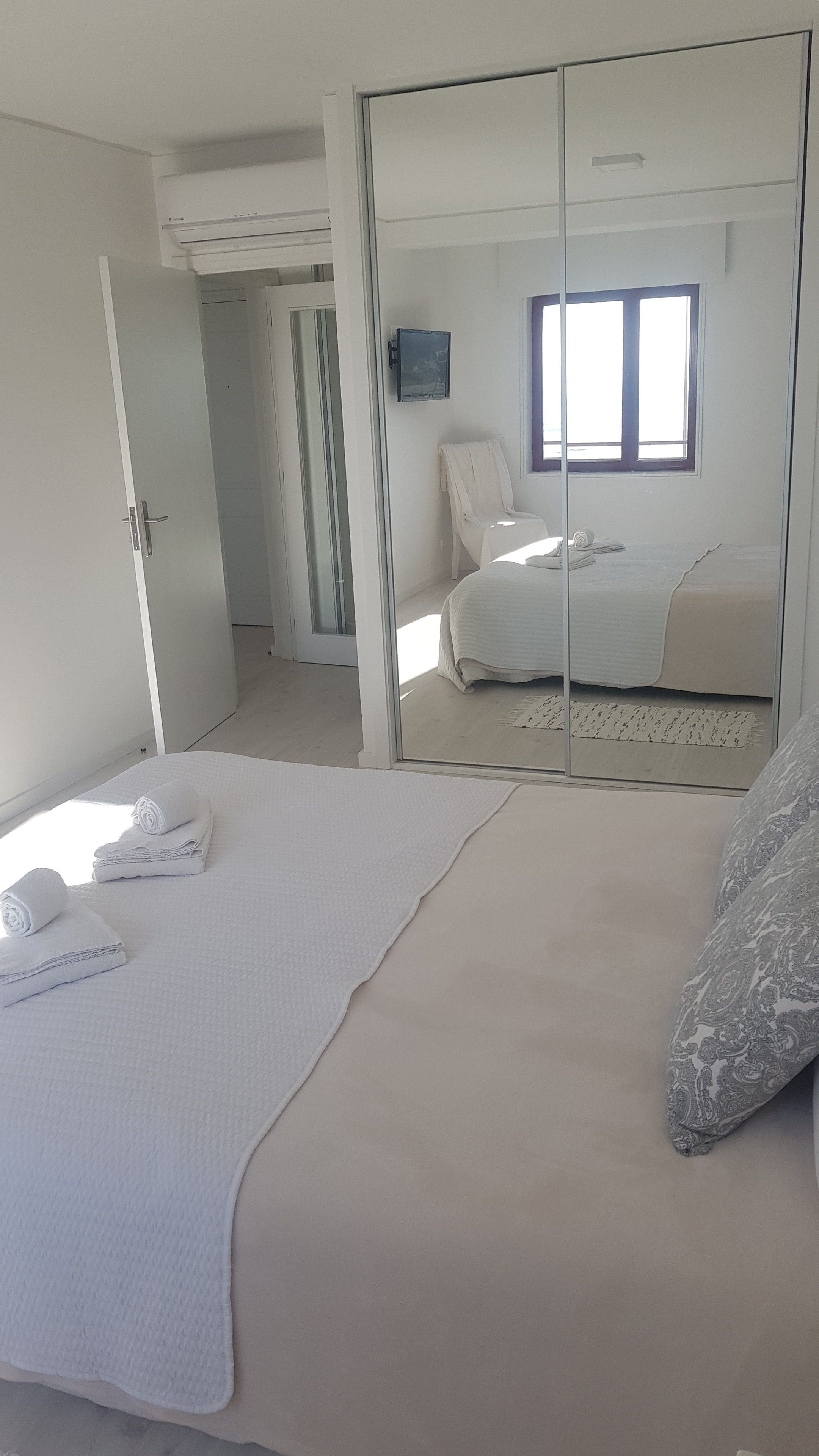 A bedroom with a bed, a chair, a wardrobe, and a window.