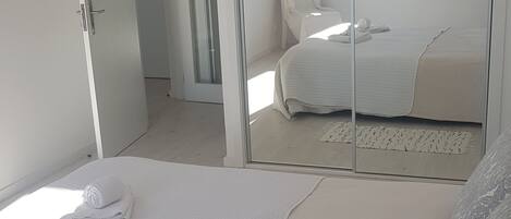 A bedroom with a bed, a chair, a wardrobe, and a window.