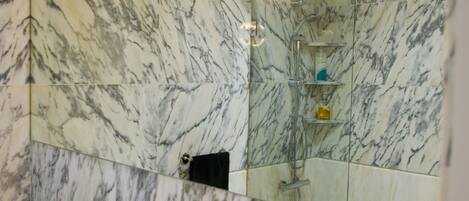 Une salle de bain avec un lavabo en marbre, un miroir, une douche et des toilettes.
