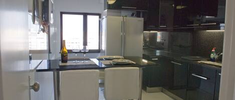 Una cocina moderna con refrigerador, pileta doble y dos taburetes de bar.
