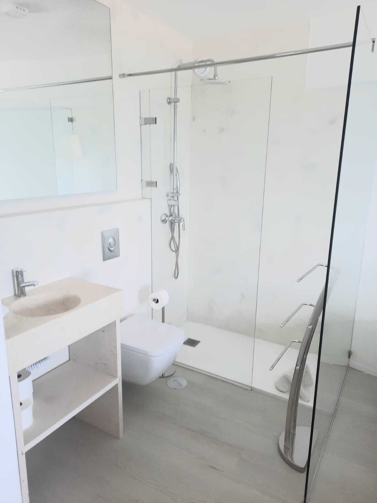 A modern bathroom with a glass shower enclosure, a sink, and a toilet.
