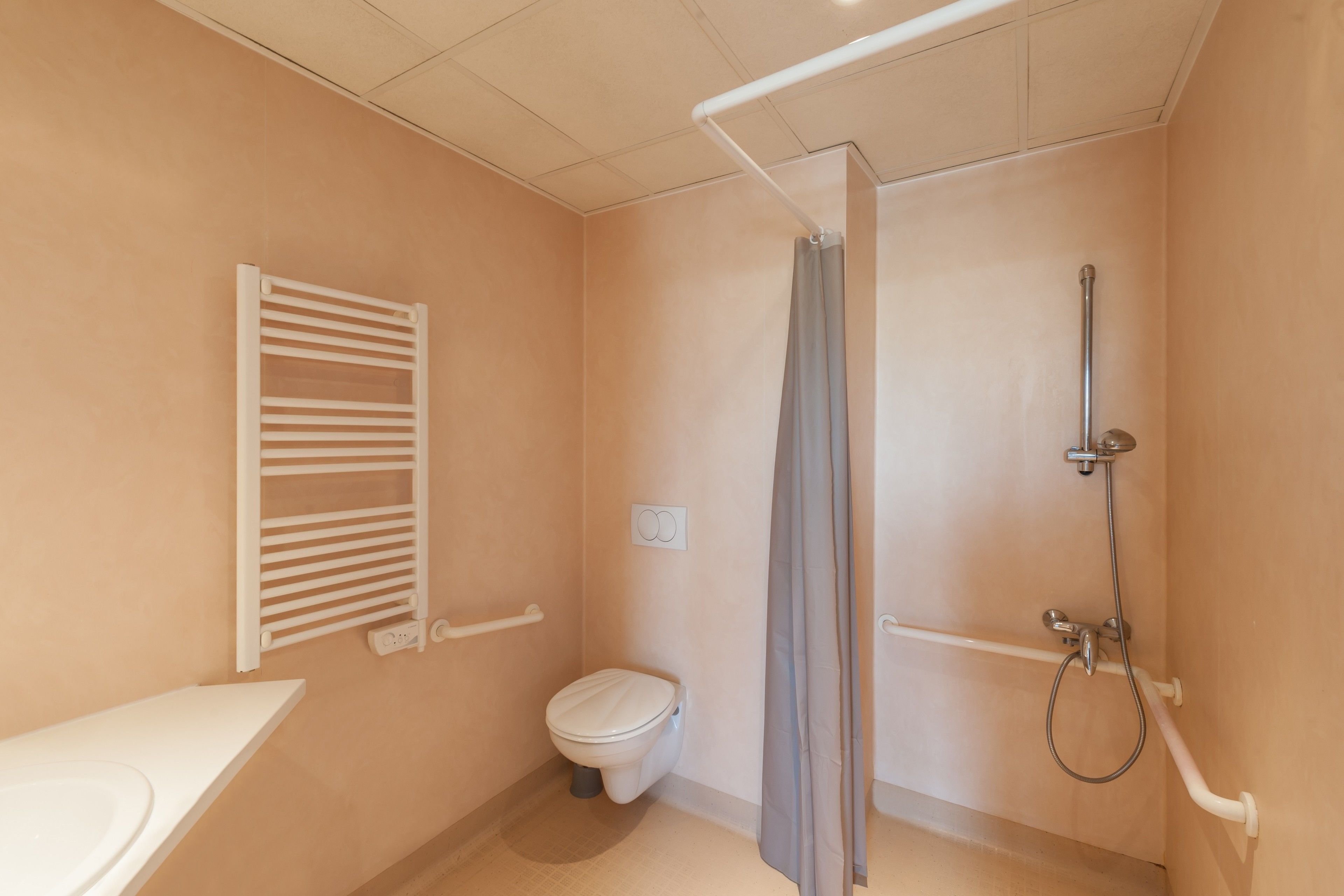 Une petite salle de bain composée d’une seule pièce, comprenant des toilettes, une douche et un porte-serviettes.
