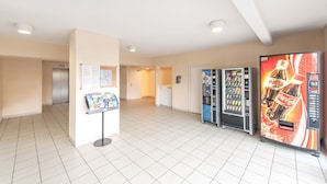 A spacious lobby with vending machines, a bulletin board, and a clean tiled floor.
