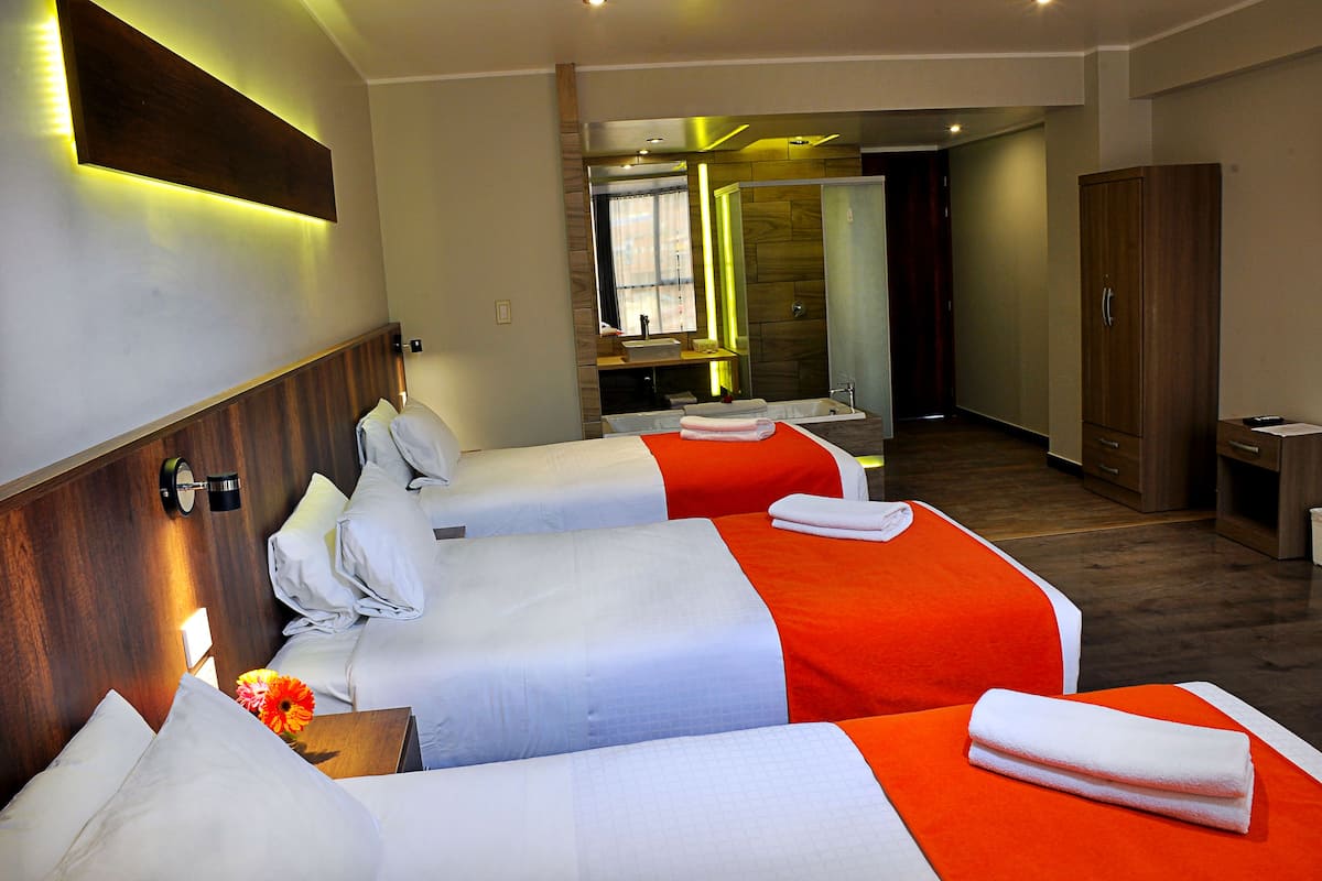 A hotel room with two beds, a bathroom, and a wooden wardrobe.
