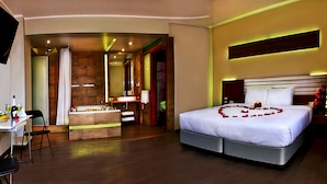 Een hotelkamer met een groot bed, een bureau met stoel, een kleine badkamer en een spiegel.