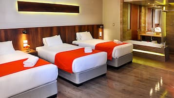 A hotel room with three beds, a large mirror, and a modern bathroom.
