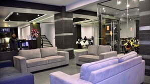 Een moderne lobby met banken, een receptiebalie en een trap.