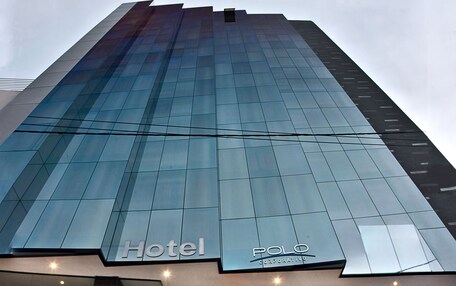 A modern hotel entrance with a glass facade, a visible staircase leading to the lobby, and the hotel's name "Hotel Polo Corporate" displayed prominently.