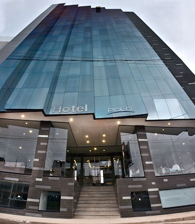 A modern hotel entrance with a glass facade, a visible staircase leading to the lobby, and the hotel's name "Hotel Polo Corporate" displayed prominently.