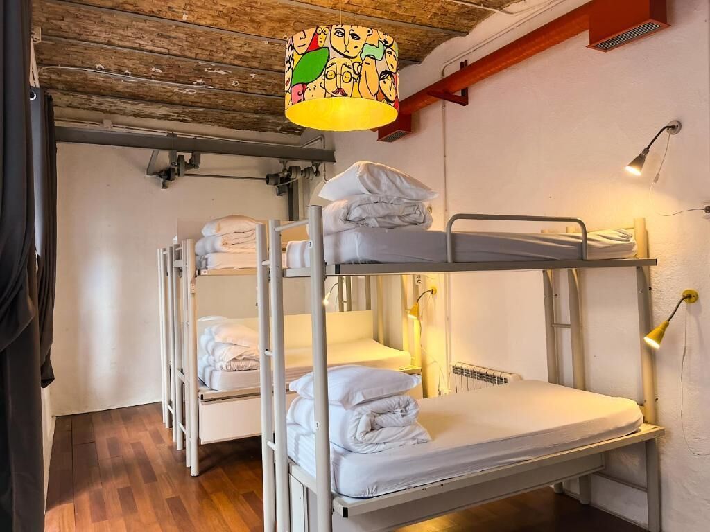 Habitación con literas, techo de madera, lámpara colgante y radiador.