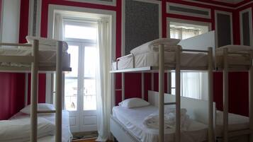 Ein Zimmer mit Etagenbetten, einem Vorhangfenster und einer Tür.
