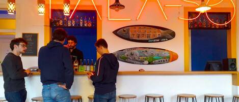 Un bar avec une enseigne au néon sur laquelle on peut lire « FALASO » et une fresque représentant un paysage urbain.