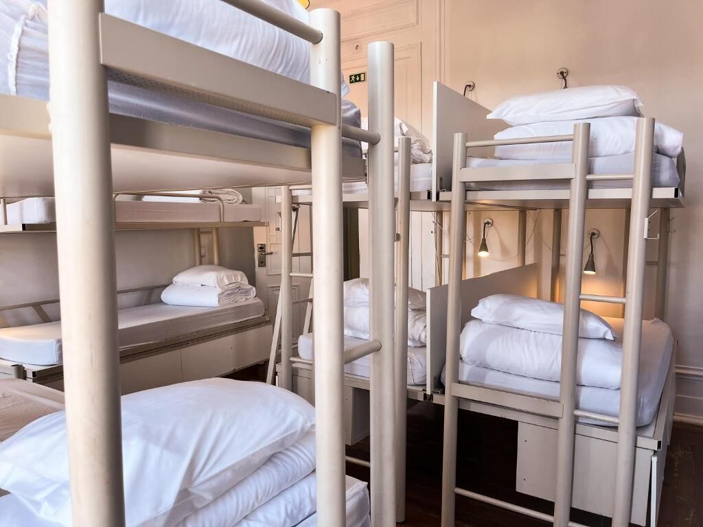 A bunk bed room with white bedding and a light fixture above the beds.