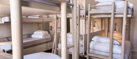 A bunk bed room with white bedding and a light fixture above the beds.