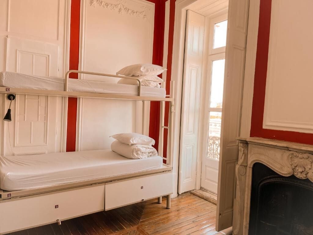 Una habitación con literas, chimenea y puerta que da a un balcón exterior.