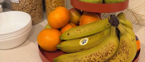 Una exhibición de frutas con peras, plátanos y naranjas sobre una mesa.