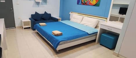 A bedroom with a bed, a nightstand, a dresser, and a colorful abstract painting on the wall.