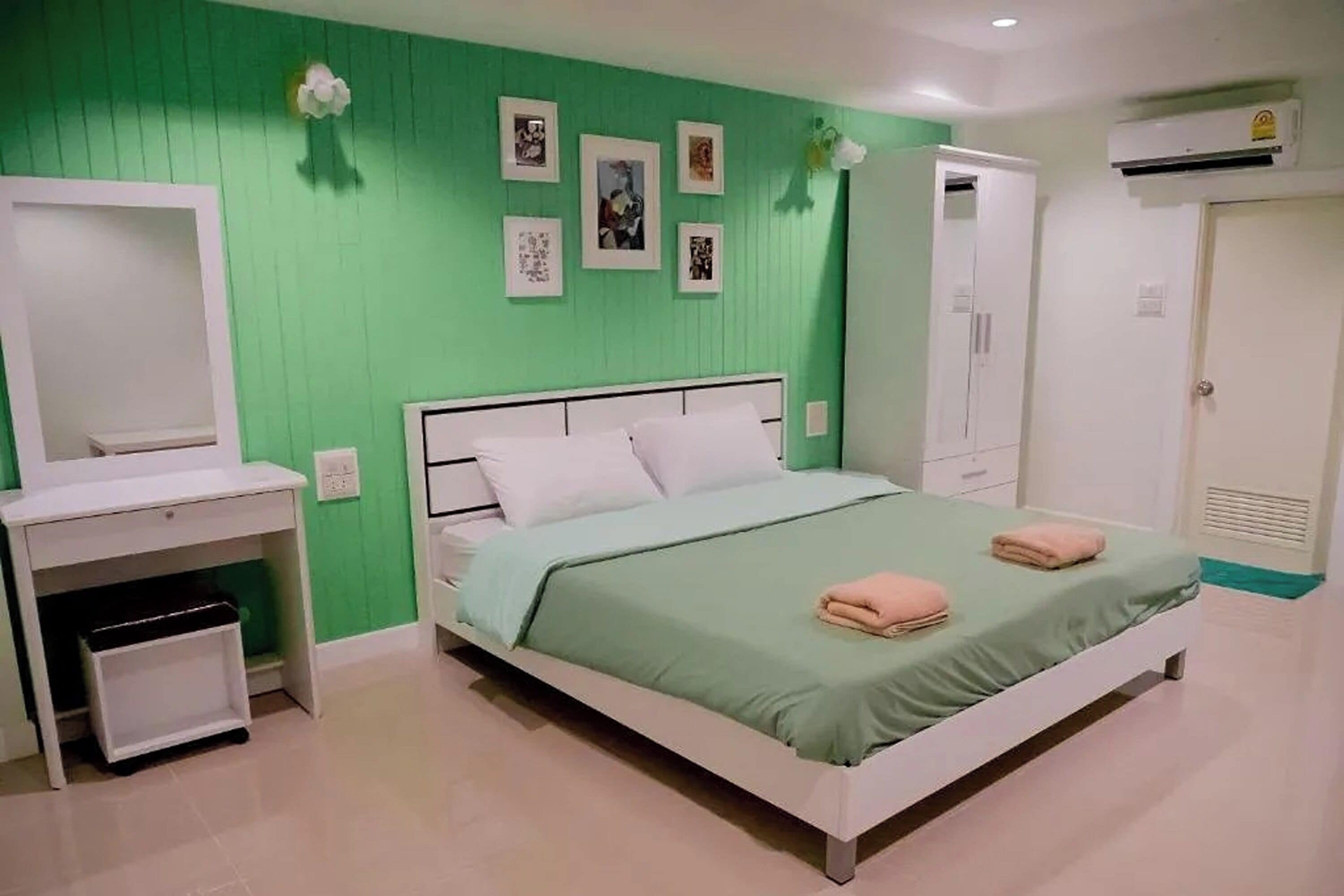 A bedroom with a bed, a wardrobe, a desk, and a mirror.