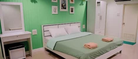 Un dormitorio con cama, armario, escritorio y espejo.