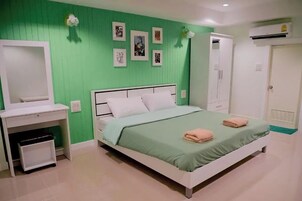 A bedroom with a bed, a wardrobe, a desk, and a mirror.