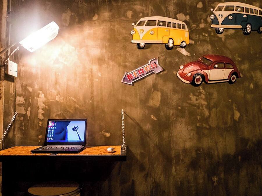A room with a desk, a laptop, and a wall decorated with vintage car stickers.