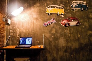 Una habitación con un escritorio, una computadora portátil y una pared decorada con calcomanías de autos antiguos.