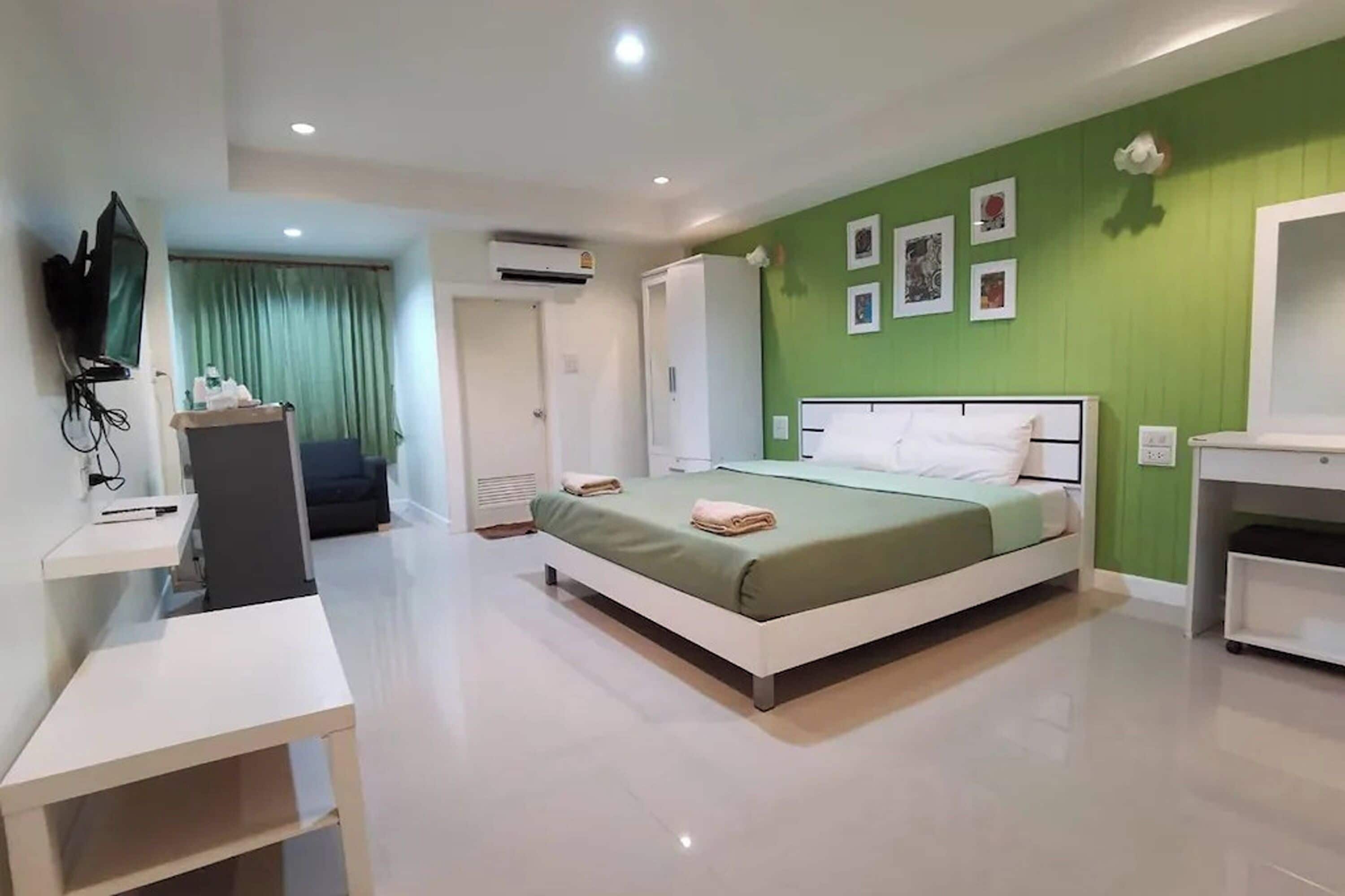 A modern bedroom with a bed, a desk, a wardrobe, and a television.