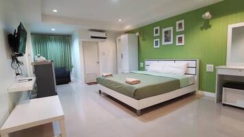 A modern bedroom with a bed, a desk, a wardrobe, and a television.
