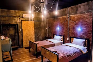 Una habitación con dos camas individuales, piso de madera y pared de ladrillo.