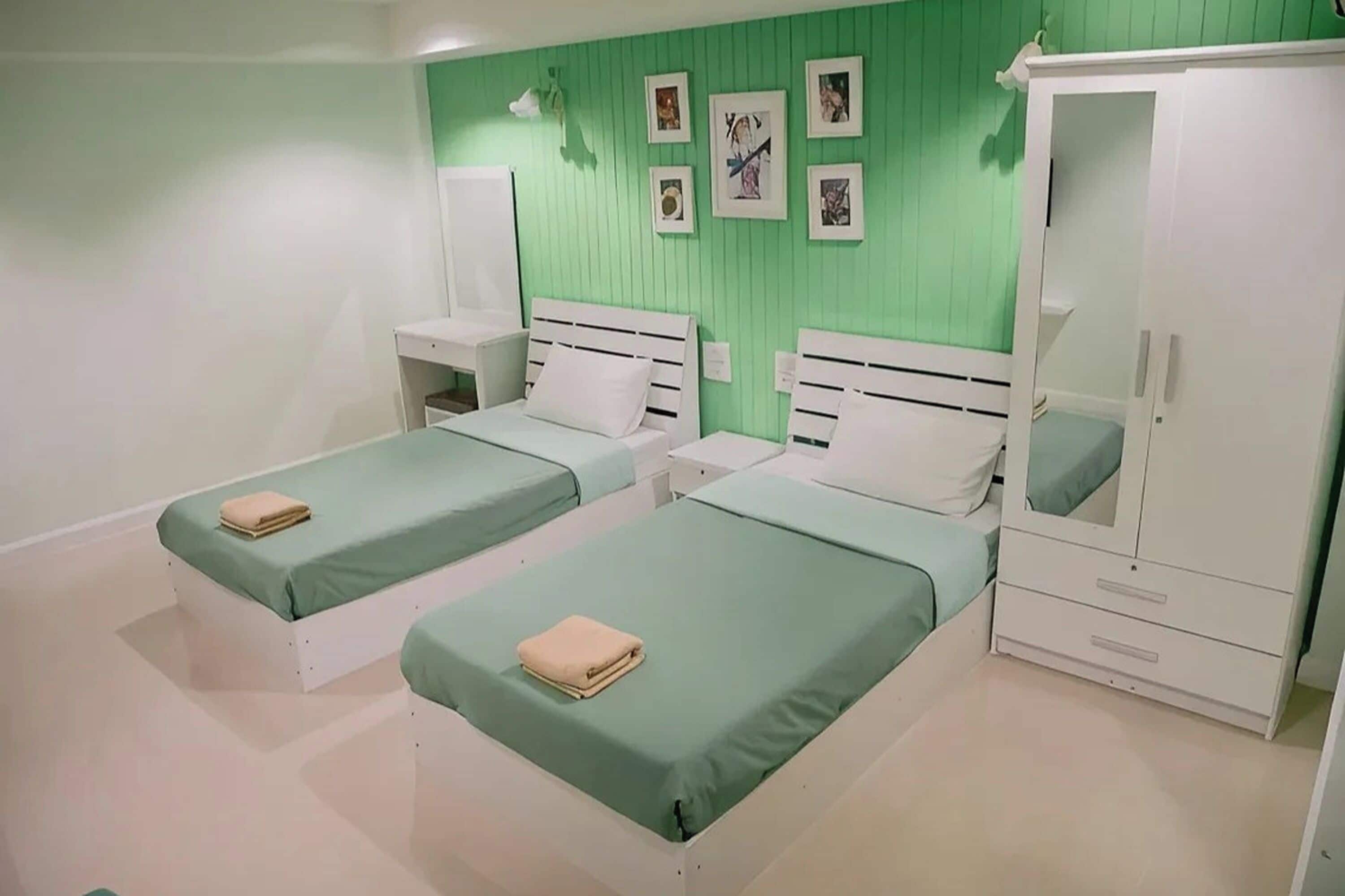 A room with two beds, a wardrobe, and a mirror.