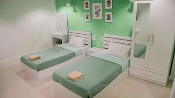 A room with two beds, a wardrobe, and a mirror.