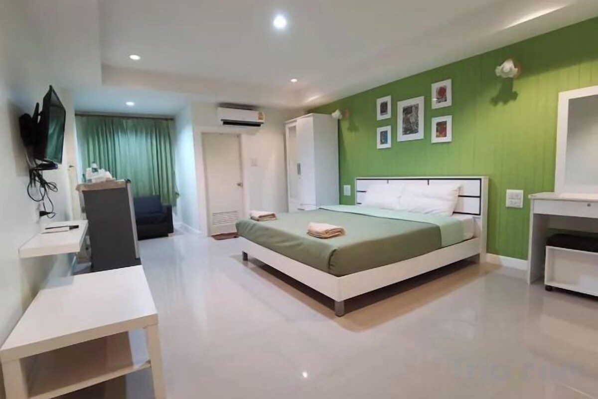 A hotel room with a bed, a desk, a TV, and a wardrobe.
