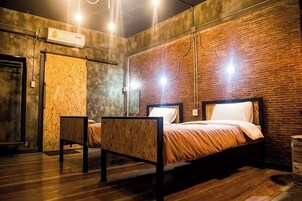 Una habitación con una cama, una silla y un muro de ladrillo.