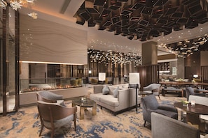 A spacious lobby with a fireplace, seating area, and modern decor. - Hilton Shenyang (Shenyang)