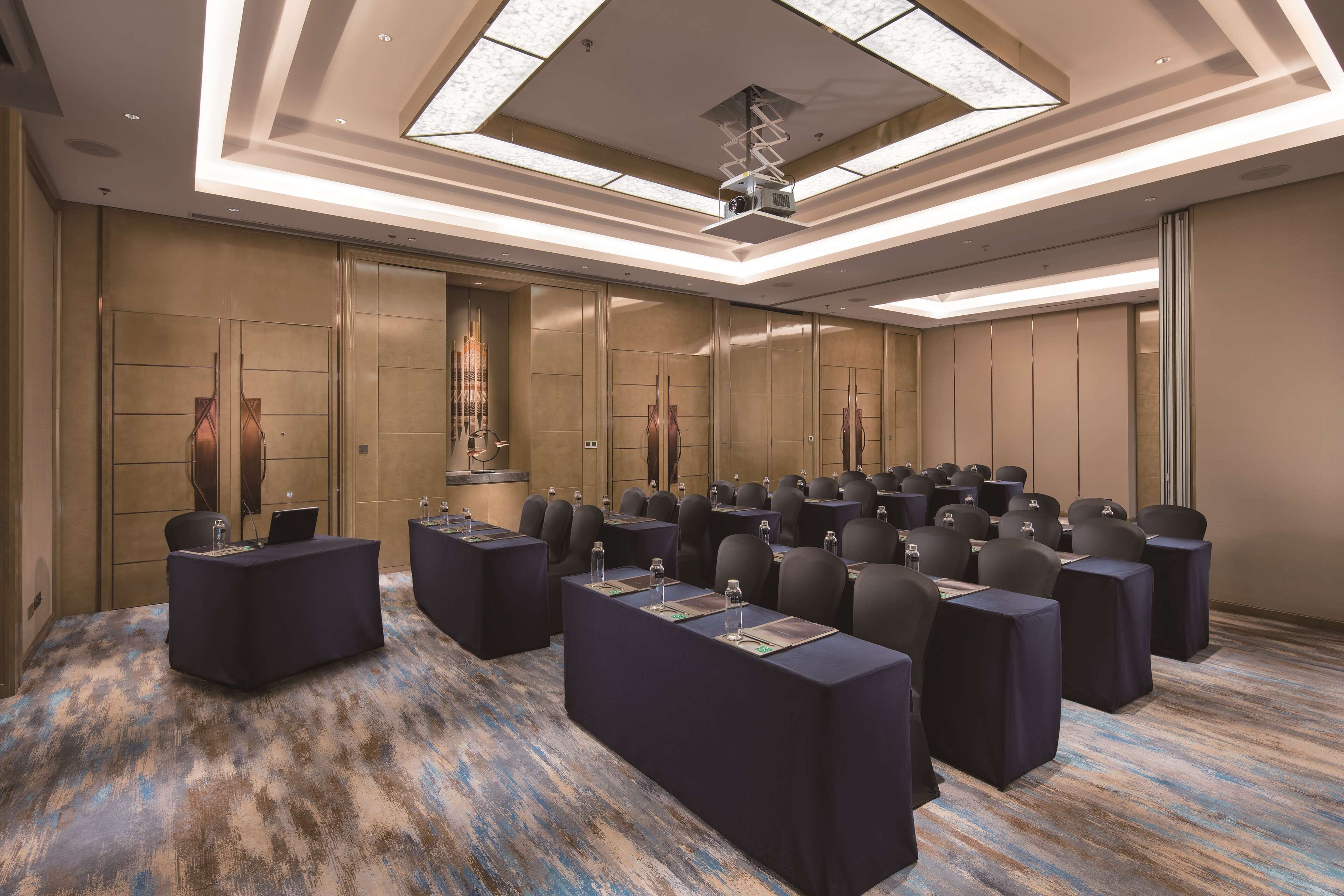 Un salón de conferencias con un diseño moderno en el techo, un atril central y filas de sillas.