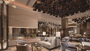Eine geräumige Lobby im modernen Design mit Kamin, gemütlichen Sitzbereichen und einer außergewöhnlichen Deckenleuchte.