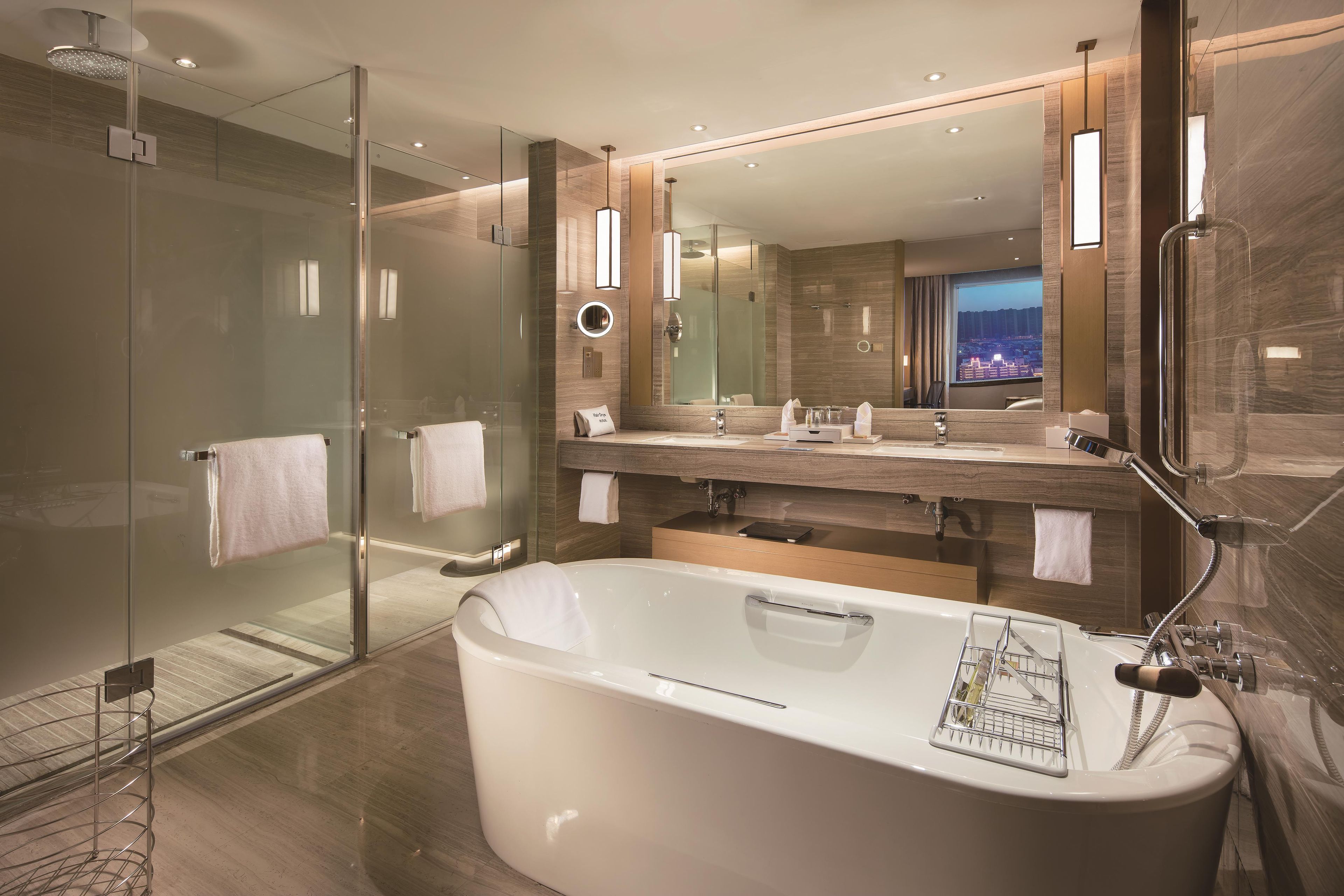 A modern bathroom with a glass-enclosed shower, a large bathtub, and a vanity with a mirror.